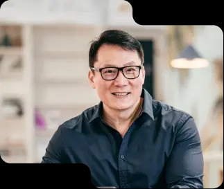 Smiling business professional in a smart navy shirt, with glasses, exuding expertise and approachability, reflective of the customer-focused service at our cryptocurrency exchange.