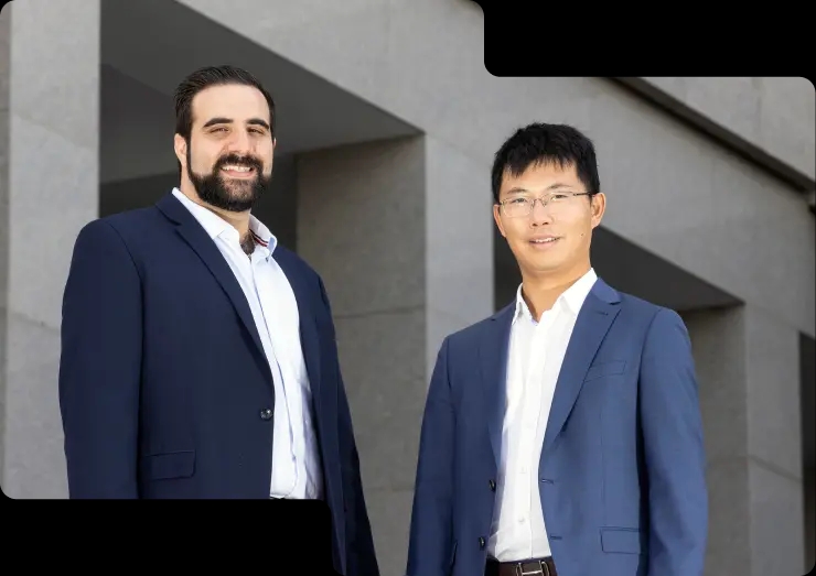 Image of the Coinstash co-founders, Mena Theodorou, who is wearing a navy suit with a red-striped tie, and Ting Wang, who is in a blue suit with glasses. Both exude leadership and vision, set against a backdrop of Brisbane city, where Coinstash is headquartered.